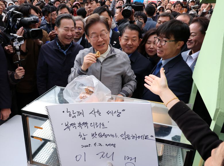 민심을 청취하는 '경청 투어'에 나선 이재명 더불어민주당 대선후보가 3일 강원도 태백시 장성중앙시장에서 잉어빵을 파는 상인에게 방명록을 남기고 인사하고 있다.태백=뉴시스