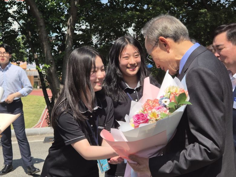 이명박 전 대통령이 동지여고 학생에게 환영의 꽃을 받고 기뻐하고 있다.