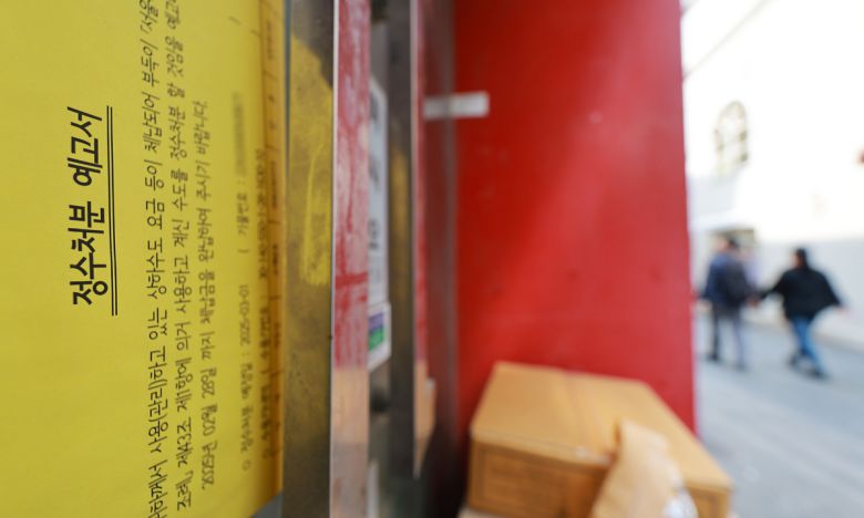 서울 명동거리의 한 폐업한 카페 출입문에 정수처분 예고서가 붙은 모습. 연합뉴스