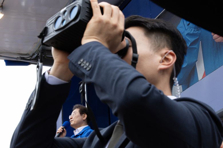 더불어민주당 이재명 대선 후보가 지난 16일 전북 군산시 구시청광장에서 열린 유세에서 지지를 호소하는 연설을 하는 가운데 경호원이 주위를 살피고 있다. 연합뉴스