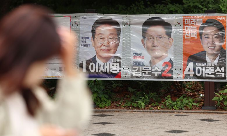 제21대 대선을 열하루 앞둔 23일 서울 마포구 공덕오거리 인근에 걸린 대선 후보 벽보 앞으로 시민이 지나고 있다. 연합뉴스