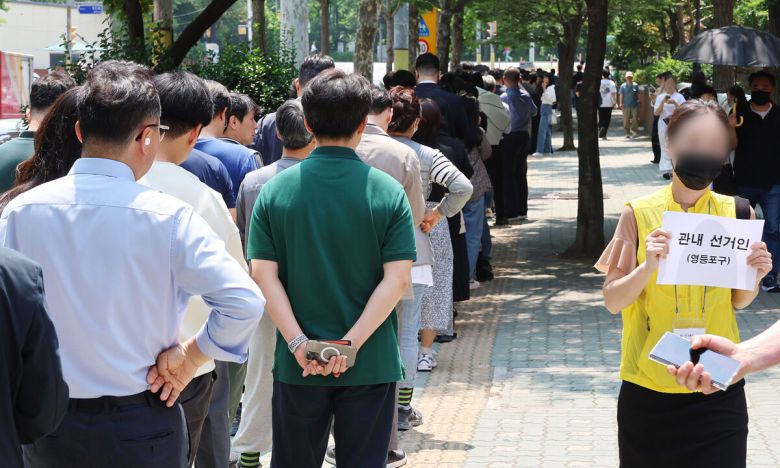 제21대 대통령 선거 사전투표 첫날인 29일 사전투표소가 설치된 서울 영등포구 여의동 주민센터 앞에 직장인들이 점심시간을 이용해 투표하기 위해 길게 줄지어 서 있다. 연합뉴스