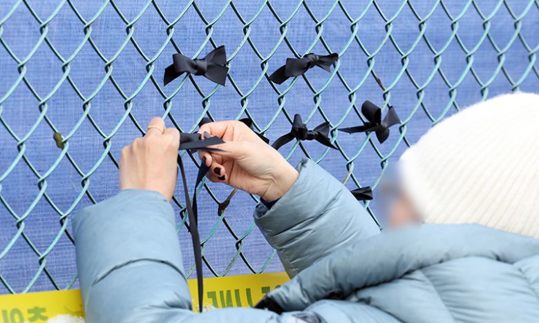 제주항공 참사 2주째인 지난 1월 11일 무안국제공항에서 유가족들이 사고 현장 인근 철조망에 검은 리본을 달고 있다. 연합뉴스