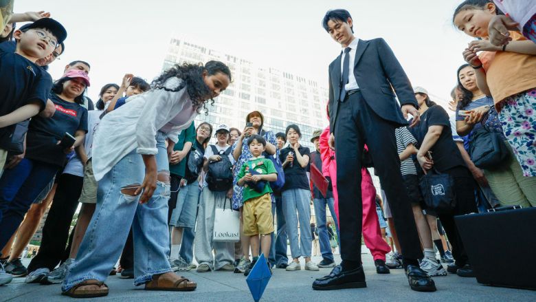 29일 서울 종로구 광화문광장에서 '2025 K콘텐츠 서울여행주간: 소울스팟을 찾아라' 행사의 일환으로 마련된 넷플릭스 오징어 게임 체험존에서 외국인 관광객이 딱지치기를 하고 있다.