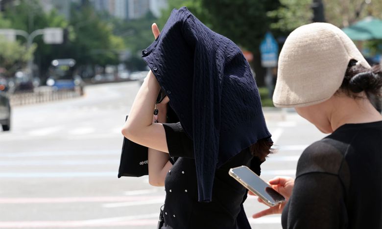 서울 광화문사거리에서 한 시민이 옷으로 햇볕을 피하고 있다. 연합뉴스