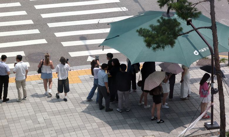 8일 서울 중구 을지로1가사거리에서 시민들이 햇볕을 피해 그늘막 아래서 신호를 기다리고 있다. 뉴시스