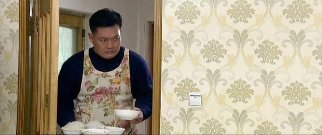 조선중앙TV 드라마 '백학벌의 새봄' 속 남성이 꽃무늬 앞치마를 입고 아내와 딸에게 밥을 차려주고 있다. 연합뉴스(조선중앙TV 캡처)