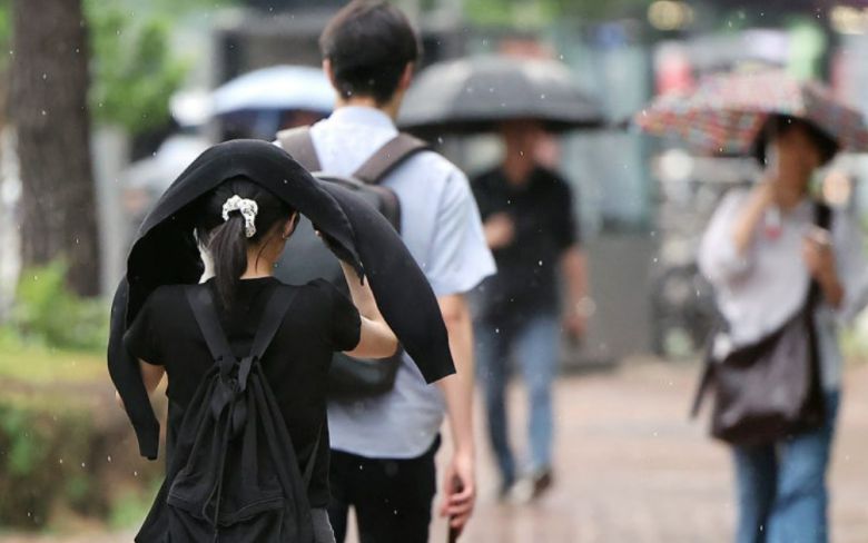 우산을 준비 못한 한 시민이 외투로 머리를 가리며 이동하고 있다. 뉴스1