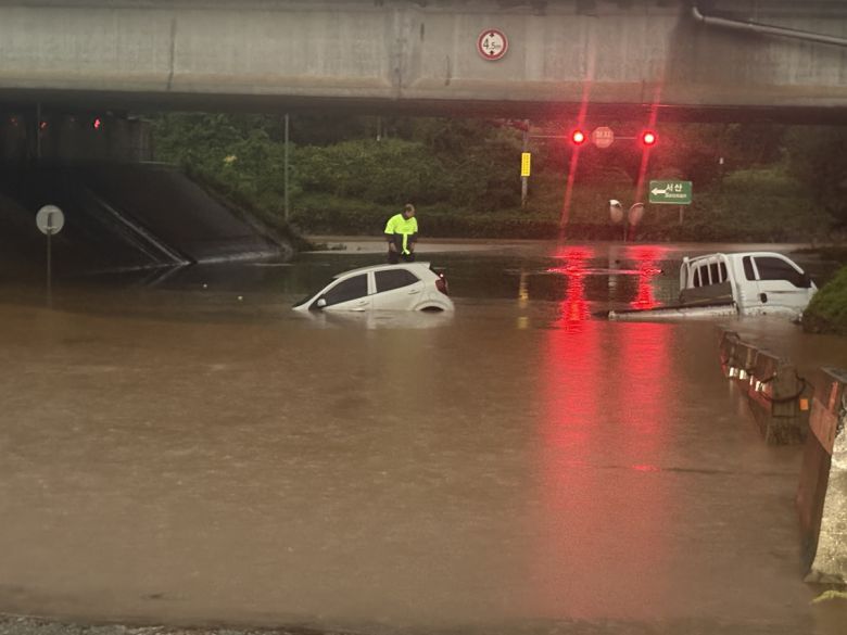17일 호우경보가 내려진 충남 서산시 운산면 운산교차로 지하차도에 침수가 발생해 차량 2대가 물에 잠겨있는 가운데 스파크 운전자가 차 위에서 구조를 기다리고 있다. 뉴시스