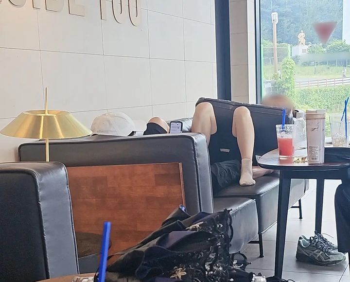카페 소파에 드러누워 휴대전화를 보는 남녀. 사진=보배드림