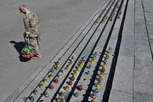5일(현지시간) 우크라이나 수도 키이우의 독립 광장에 마련된 임시 전몰 장병 추모 공간 앞에서 한 병사가 꽃을 든 채 이동하고 있다. AFP연합뉴스