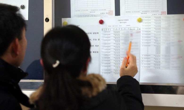 서울 서초동 서울중앙지방법원 경매법정 앞에서 응찰 예정자들이 게시물을 살피고 있다. 연합뉴스