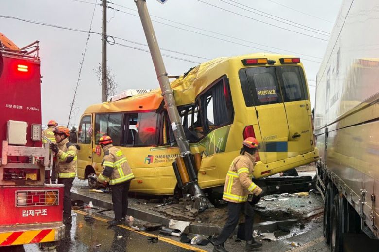 지난 23일 오후 4시26분쯤 전북 김제시 백산면 상정리 지평선산단로 돌제교차로에서 초등학교 스쿨버스가 화물 윙바디 트럭과 충돌한 뒤 안전지대에 세워진 신호등과 추돌하는 사고가 나자 119 구급대원들이 분주하게 움직이고 있다. 전북도소방본부 제공