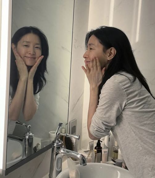 배우 이영애가 세면대 앞 거울을 보며 양손을 뺨에 대고 미소 짓는 장면. 이영애 인스타그램 캡처