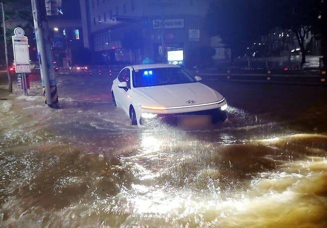 호우경보가 발효된 13일 부산 사상구의 한 도로가 침수돼 택시가 힘겹게 이동하고 있다. 부산소방재난본부 제공