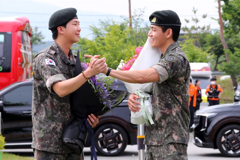 군 복무를 마친 방탄소년단 RM(왼쪽), 뷔가 10일 오전 강원 춘천시 한 부대 인근에서 전역인사를 하고 있다. 뉴시스 제공.