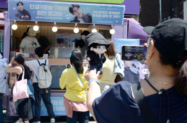 11일 방탄소년단(BTS)의 지민과 정국이 군 복무를 마치고 만기 전역했다. 서울 용산구 하이브 사옥 인근에는 RM과 뷔의 전역을 축하하기 위해 글로벌 아미들이 모였다. 한 여성팬이 커피트럭 앞에서 캐릭터 인형을 찍고 있다. 김용학 기자