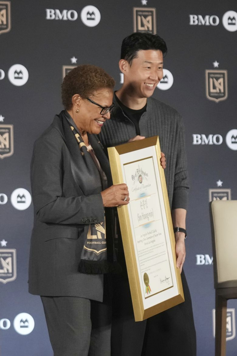 손흥민(오른쪽)이 7일 미 캘리포니아주 로스앤젤레스(LA)의 BMO 스타디움에서 미국프로축구(MLS) LA FC 입단 기자회견을 하면서 캐런 베이스 LA 시장과 함께 인증서를 들고 포즈를 취하고 있다. 사진=AP/뉴시스