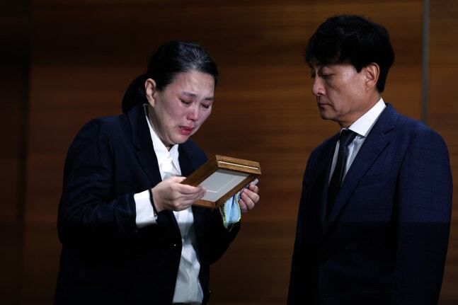 고 오요안나씨 어머니 장연미씨가 15일 오전 서울 마포구 MBC에서 열린 고 오요안나 1주기 관련 대국민 기자회견에서 안형준(오른쪽) MBC 사장에게 명예사원증을 전달 받은 후 슬퍼하고 있다. 뉴시스 제공