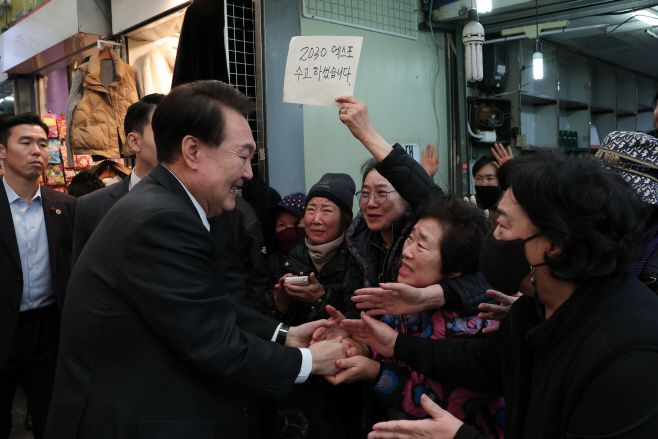 윤석열 대통령이 6일 부산 국제시장을 찾아 시민들과 인사를 나누고 있다. 응원 메시지를 든 상인./대통령실