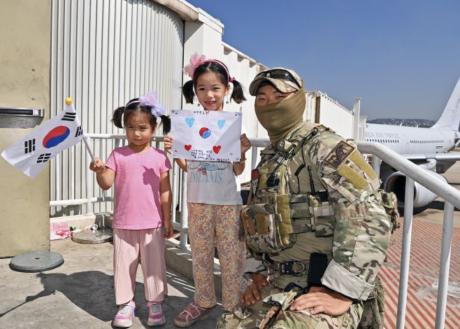 레바논 교민 김서경씨의 자녀 2명이 4일 레바논 베이루트 공항에서 '사랑해요 군인님 우리는 괜찮아요 우리를 구해주러 와서 고맙습니다'라고 적힌 손편지를 들고 교민들을 안전하게 귀환시키기 위해 도착한 우리 공군의 항공특수통제사(CCT)와 기념촬영하고 있다. 정부 신속대응팀은 이날 레바논 베이루트 공항을 출발해 교민 90여명을 무사히 인솔해 5일 서울공항에 귀환했다.  /국방부