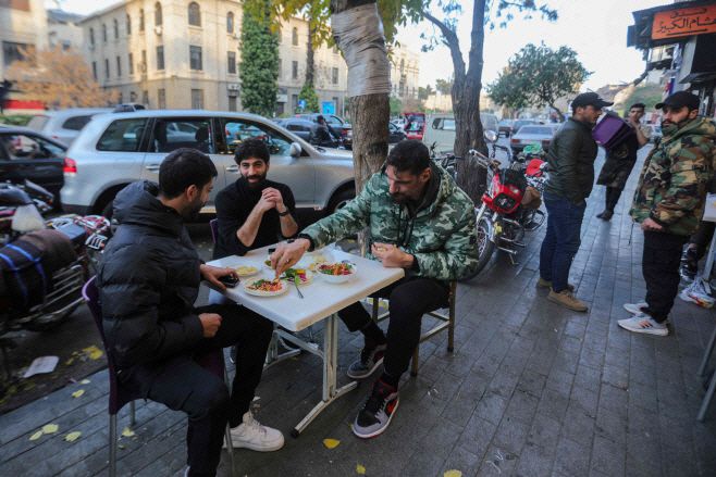 시리아인들이 9일(현지시간) 다마스쿠스의 음식점 외부에서 음식을 먹고 있다./AFP·연합뉴스