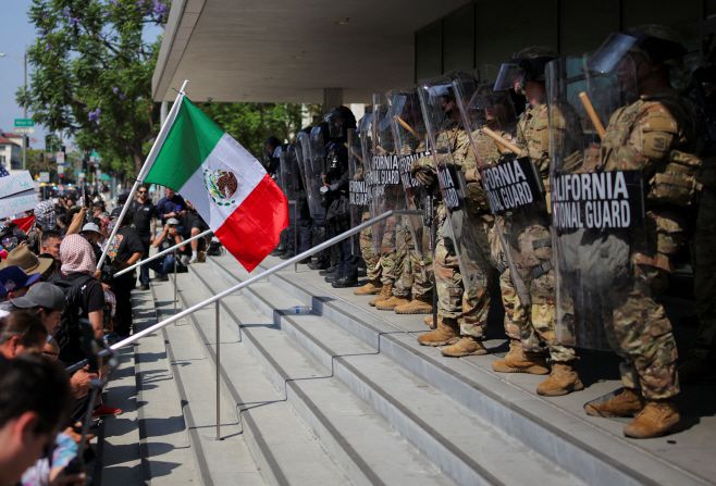 이민세관단속국(ICE)의 대대적인 불법 이민자 단속에 항의하는 시위대와 주방위군 및 경찰이 8일(현지시간) 캘리포니아주 로스앤젤레스(LA)에서 대치하고 있는 가운데 한 시위자가 멕시코 국기를 흔들고 있다./로이터·연합