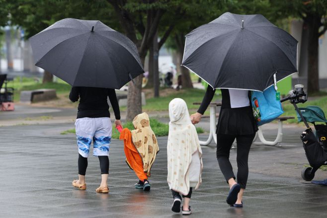 비가 내리며 폭염주의보가 해제된 13일 서울 여의도물빛광장에서 물놀이를 즐기던 시민들이 비를 피해 이동하고 있다./연합