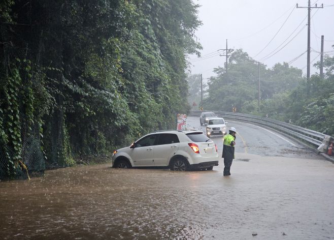 전국 곳곳에 밤새 폭우가 내린 20일 강원 춘천시 서면 오월리 한 도로 물웅덩이에 SUV 차량이 빠져 있다. /연합