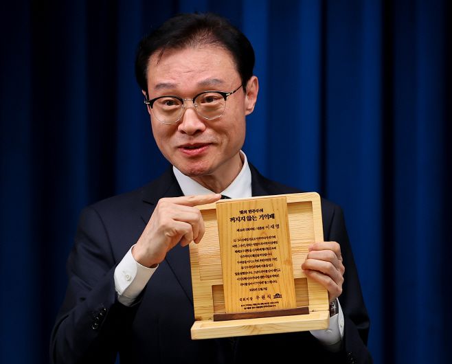 이규연 홍보소통수석이 3일 용산 대통령실에서 이날 진행된 이재명 대통령과 5부 요인 오찬 간담회에서 우 의장이 이 대통령에게 전달한 기념패를 들어 보이고 있다.'빛의 민주주의 꺼지지 않는 기억패'라고 이름 붙은 이 기념패는 계엄군이 국회에 난입하는 과정에서 부서진 목재 집기를 활용해 만들었다./연합뉴스
