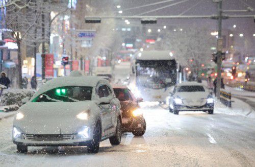 Cars struggle up a snow-covered hill past an area where snow removal has not yet been completed near Hongdae in Mapo-gu, Seoul, on December 4, as a heavy snow advisory is in effect. / Source: Yonhap News