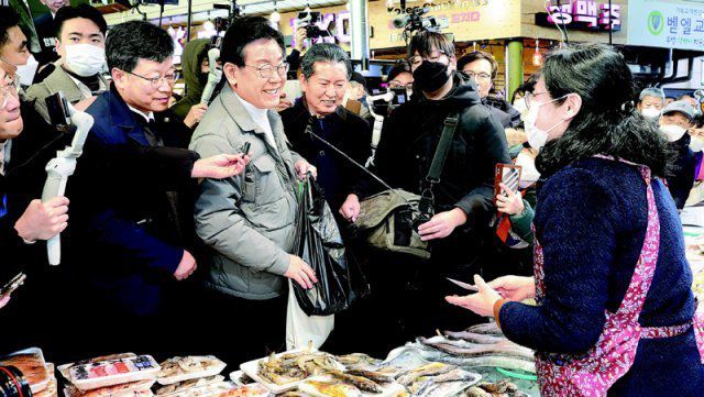 망원시장 찾은 이재명 더불어민주당 이재명 대표(앞줄 왼쪽에서 세 번째)가 18일 서울 마포구 망원시장에서 상인과 대화하고 있다. 이 대표는 이날 대장동  및 위례신도시 개발사업 특혜 의혹과 관련한 검찰의 출석 통보에 대해 “오늘 우리의 검찰은 질서 유지를 위해 공정하게 권한 행사를  하는 게 아니라 자신들의 사적 이익을 위해서 편파적으로 권력 남용을 한다”고 비판했다. 사진공동취재단