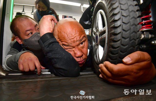 <사건사고 뉴스> 4월 21일 서울 지하철 2호선 시청역에서 출근길 지하철 탑승 시위를 재개한 전국장애인차별철폐연대(전장연) 회원들이 휠체어에서 내려 지하철에 기어서 탑승한 뒤 휠체어의 바퀴를 잡고 있다.당시 휠체어에는 문애린씨(42)가 타고 있었으며, 지하철 탑승 시위에 항의하는 한 시민에게 “죄송합니다, 저희도 함께 살아가고 싶습니다”라고 대답하고 있었다. 이 모습을 본 전장연 회원들은 기어서 문 씨의 휠체어 바퀴를 잡는 모습을 담았다. /최현규 국민일보 기자