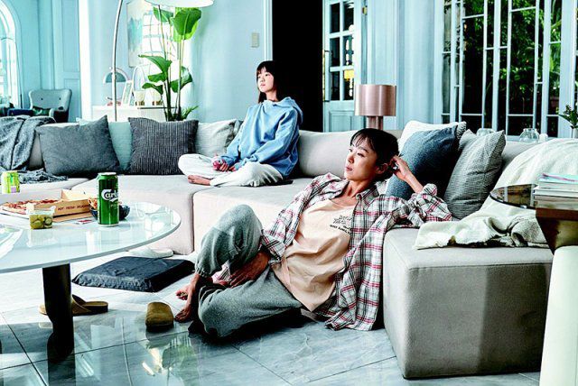 영화 ‘길복순’에서 복순(전도연·오른쪽)이 사춘기 딸 재영(김시아)과 멀찍이 떨어져 TV를 보고 있다. 복순은 밤에는 킬러지만 낮에는 말 안 듣는 딸의 엄마로 지낸다.