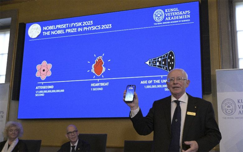 스웨덴 왕립과학원 관계자(오른쪽)가 3일 아토초 펄스광 개발에 기여한 과학자 3명을 올해 노벨 물리학상 수상자로 발표하고 있다.  스크린에는 심장이 약 1초에 한 번 뛴다는 설명과 함께 ‘아토초는 100경분의 1초’라는 설명이 적혀 있다. 스톡홀름=AP 뉴시스