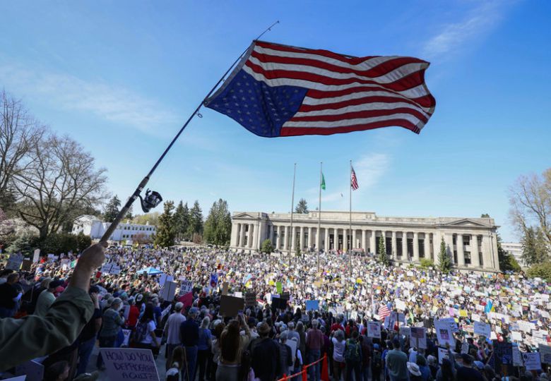 미국 워싱턴주 주도인 올림피아의 주의회 앞에서 열린 시위에서는 한 참여자가 성조기를 낚싯대에 거꾸로 매달아 흔들었다. 미국에서 ‘거꾸로 매단 성조기’는 저항의 의미로 여겨진다. 올림피아=AP 뉴시스