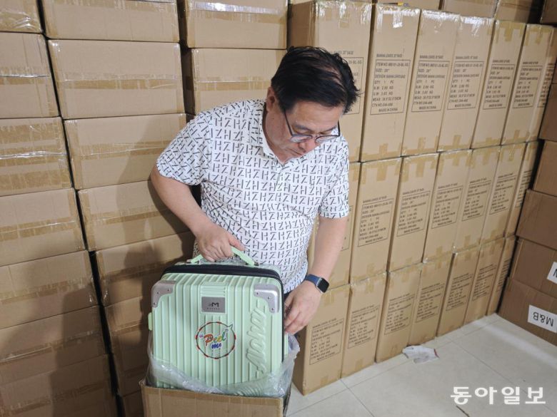 21일 이우시에서 무역업을 하는 곽병규 사장이 미국 하와이 업체로 납품하려다 인도가 지연돼 창고에 쌓아 높은 여행용 가방(캐리어)를 꺼내 보이고 있다. 이우시=김철중 특파원 tnf@donga.com