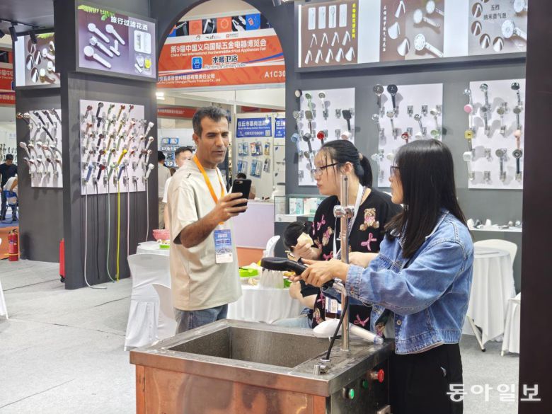 22일 중국 이우시에서 열린 ‘국제 금속 전기 박람회’에서 한 바이어가 샤워기 꼭지의 시연 모습을 휴대폰 카메라로 찍고 있다. 이우시=김철중 특파원 tnf@donga.com