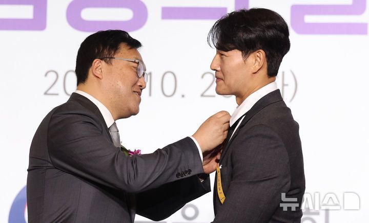 김병환 금융위원장이 2024년 10월 29일 서울 영등포구 여의도 FKI타워 컨퍼런스센터에서 열린 ‘제9회 금융의 날 기념식’에서 가수 김종국에게 대통령 표창을 전달하고 있다.