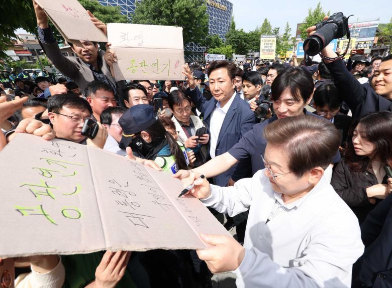 지지자들 “공판 연기 환영”에 李 “맞습니다” 더불어민주당 이재명 대선 후보가 7일 전북 전주시 완산구 풍남문 앞 광장에서 이 후보의 공직선거법 위반 사건 파기환송심 공판기일 변경을 환영하는 지지자의 응원 피켓에 사인을 해주고 있다. 이 후보는 ‘공판 연기 환영, 대통령은 국민이 뽑습니다’라고 적힌 피켓에 ‘맞습니다’라고 적었다. 전주=뉴시스