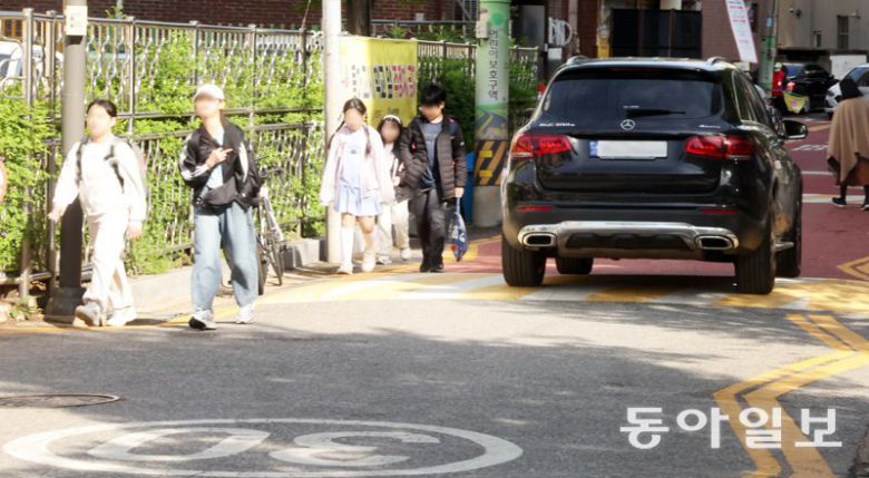 지난달 23일 서울 양천구의 한 초등학교 근처 스쿨존(어린이보호구역)에서 아이들이 인도와 차도의 구분이 없는 도로를 걸어 등교하고 있다. 아이들 옆을 차가 지나가고 있다. 장승윤 기자 tomato99@donga.com