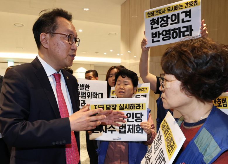 박민수 보건복지부 제2차관(왼쪽)이 21일 서울 용산구에서 열린 ‘진료지원 업무 제도화 방안 공청회’에서 항의에 나선 전국민주노동조합총연맹 공공운수노조 의료연대본부 조합원에게 설명을 하고 있다. 뉴스1