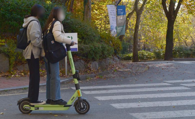 광주 북구의 한 도로에서 여성 2명이 킥보드 한 대를 함께 타고 주행하고 있다. 이는 불법이다. 광주=뉴시스