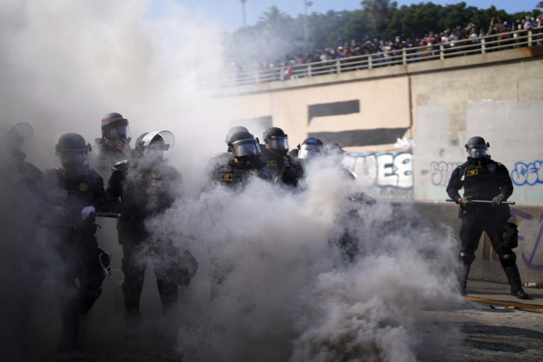 8일(현지시간) 미국 로스앤젤레스 도심 메트로폴리탄 구치소 인근 101번 프리웨이에서 전날 이민 단속에 항의하는 시위 직후 자욱한 연기 너머로 경찰이 보이고 있다. AP 뉴시스