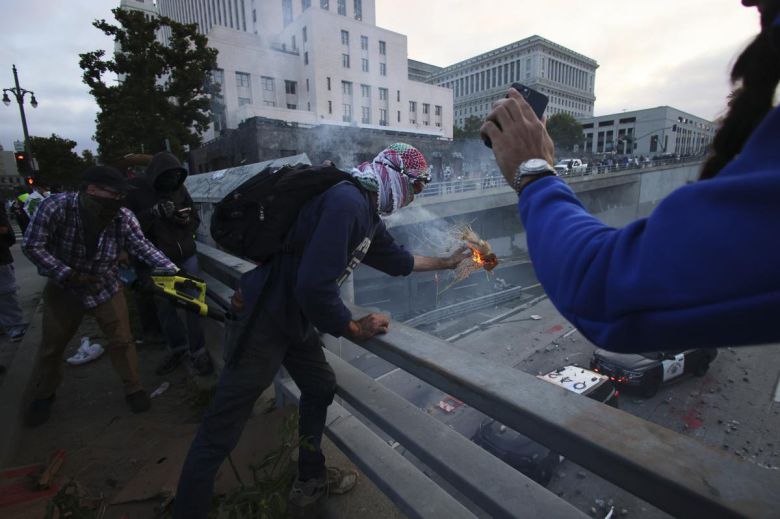 8일(현지시간) 미국 캘리포니아주 로스앤젤레스 도심 메트로폴리탄 구치소 인근 프리웨이에서 시위대가 경찰 차량을 향해 물체를 던지고 있다. AP 뉴시스