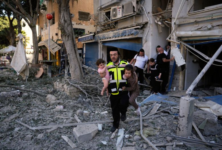 이스라엘 민간인들도 큰 피해 22일 이스라엘 북부 거점 도시 하이파에서 이란의 미사일 공격으로 건물이 무너진 가운데 한 구조대원이 어린이 두 명을 대피시키고 있다. 이란은 전날 미국이 이란의 핵 시설 3곳을 직접 타격했고, 이스라엘도 공습을 이어가고 있는 것에 따른 보복 조치로 이스라엘 전역에 탄도미사일을 발사했다. 하이파=AP 뉴시스