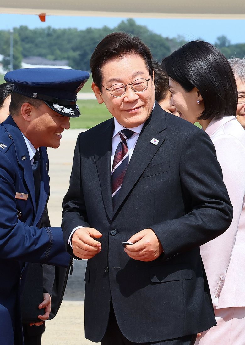 한미정상회의 참석차 미국을 방문한 이재명 대통령이 24일(현지시간) 워싱턴DC 앤드루스 통합기지에 도착해 영접나온 조슈아 킴 대령(왼쪽)으로부터 전달받은 기지방문기념 코인을 쥐고 있다. 대통령실사진기자단.