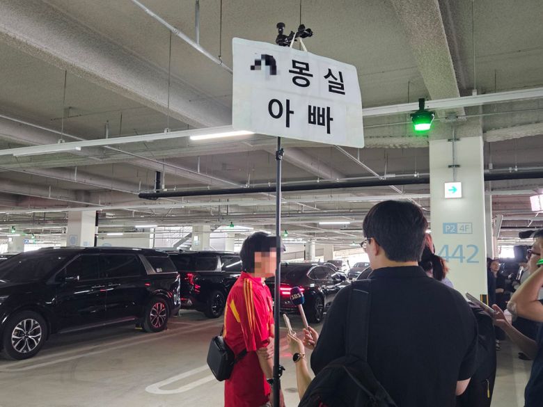 12일 미국에 구금됐다가 풀려난 한국인 직원의 귀국을 기다리는 가족이 반려견 이름이 적힌 피켓을 들고 언론 인터뷰를 하고 있다. 2025.09.12. 뉴스1