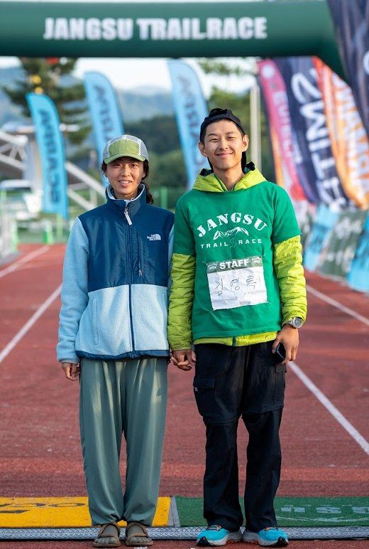 김영록 대표(오른쪽)가 아내 박하영 씨와 함께 장수트레일레이스 대회를 개최하는 전북 장수종합운동장에서  밝게 웃고 있다. 산 달리기를 좋아한 그는 트레일러닝대회를 만들어 아내 고향 전북 장수에 활기를 불어넣고 있다. 김영록 대표 제공.