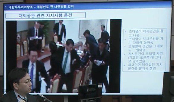 서울중앙지법 형사합의33부(부장판사 이진관) 심리로 열린 한덕수 전 국무총리 2차 공판에서 특검이 제시한 12·3 비상계엄 당일 대통령실 폐쇄회로(CC)TV 영상 화면에 비상계엄 선포 이후 윤석열 전 대통령 주재 회의가 끝나고 조태열 전 외교부 장관이 문건을 책상에 놔두고 일어서는 장면이 재생되고 있다. 특검은 재외공관 관련 지시사항이 담긴 문건이라고 설명했다. 법원 공판 중계 화면 캡처